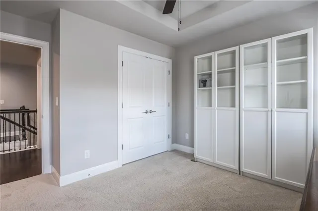 an empty room with a ceiling fan and carpet