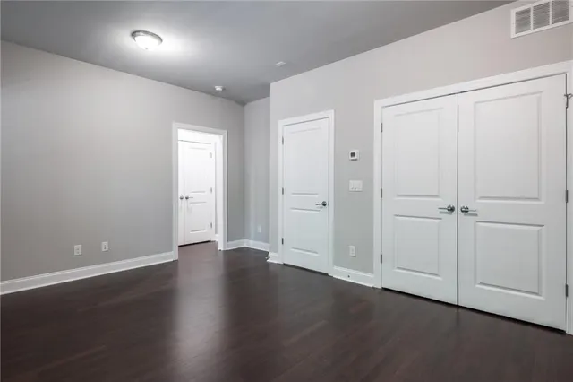 an empty room with wooden floor & closet area