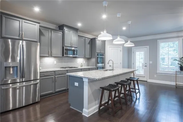 a kitchen with stainless steel appliances granite countertop a sink a stove a refrigerator and island with wooden floor