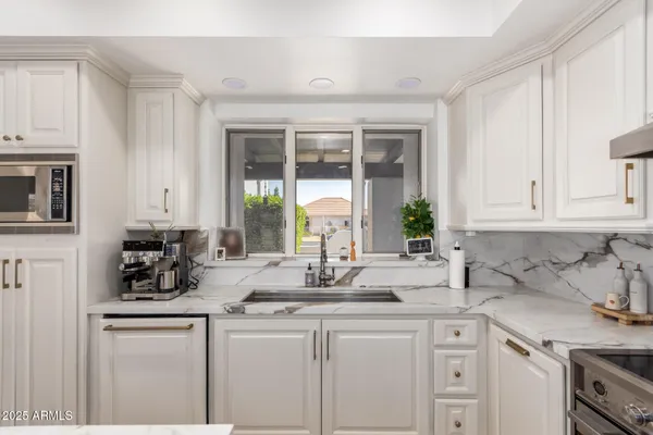 a kitchen with white cabinets and window