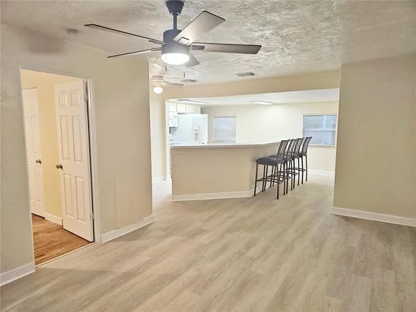 an empty room with wooden floor fan and windows