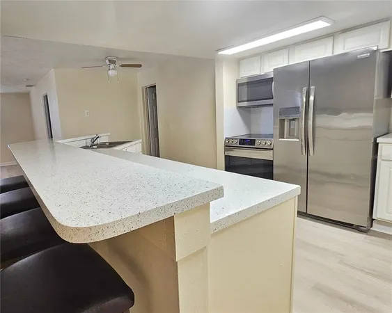 a kitchen with kitchen island a counter top a stove a refrigerator and a sink