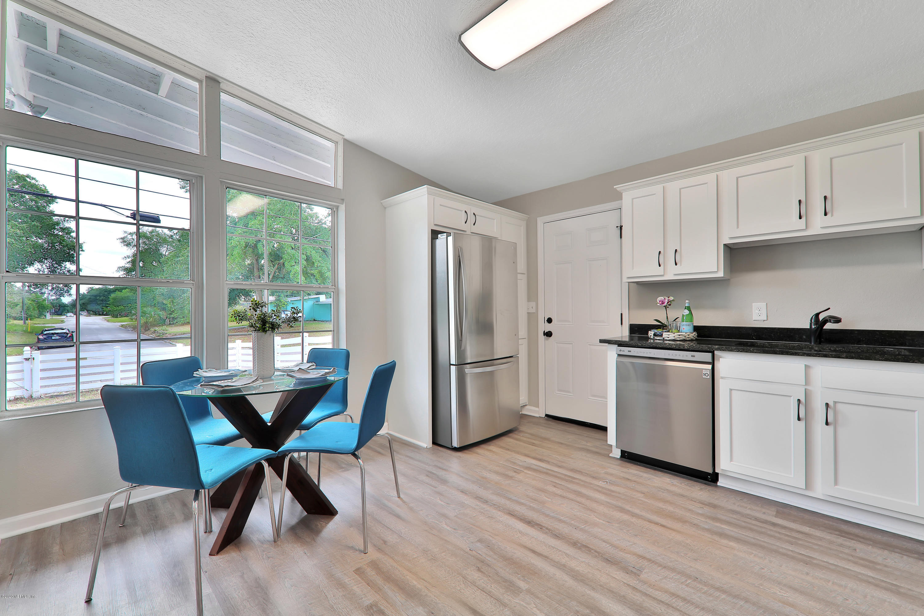 7359 Sandhurst Road South Jacksonville, FL 32277 - Photo 12 of 34 a kitchen with stainless steel appliances granite countertop a stove top oven a refrigerator a dining table and chairs with wooden floors