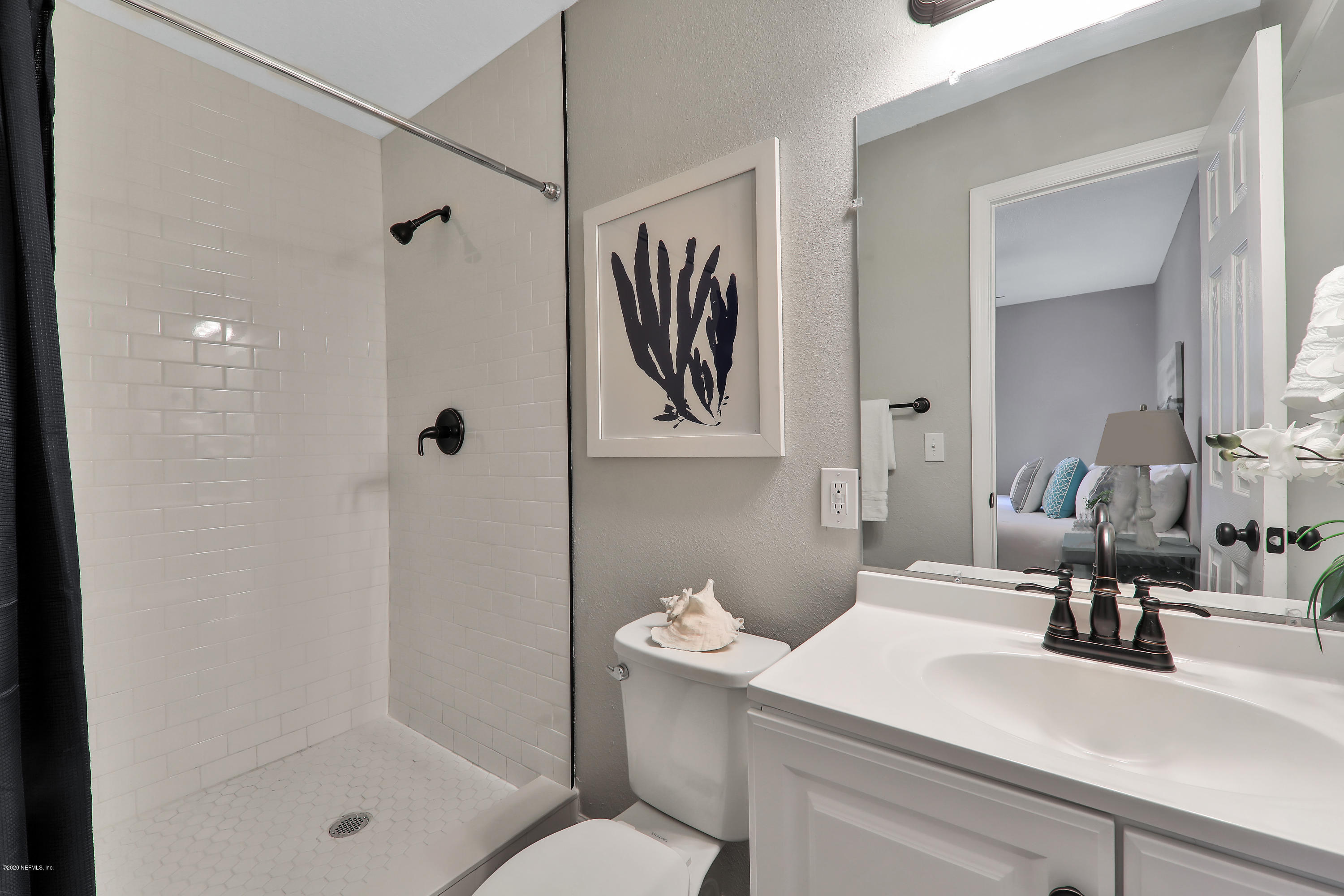 7359 Sandhurst Road South Jacksonville, FL 32277 - Photo 20 of 34 a bathroom with a sink a mirror a shower and a mirror