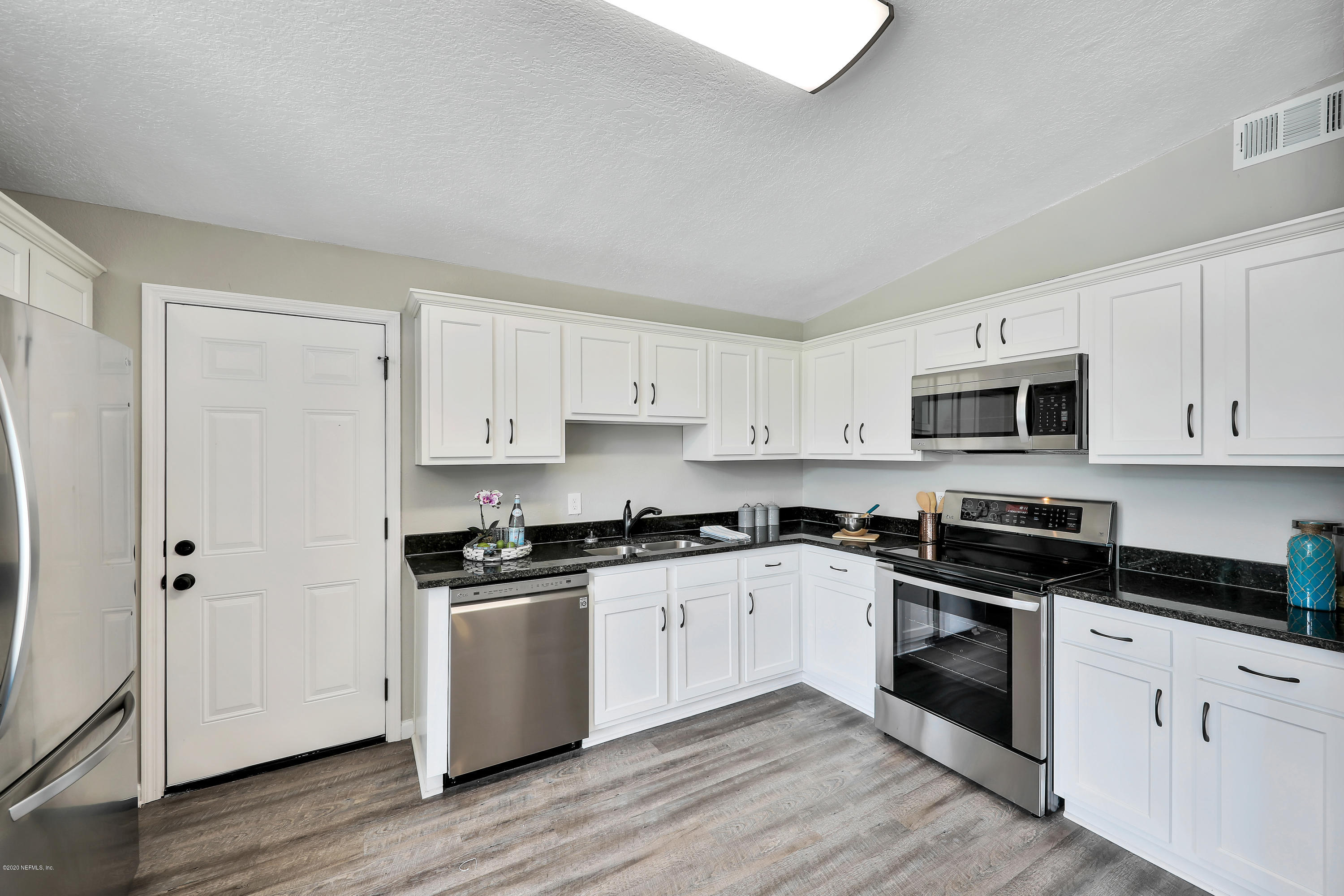 7359 Sandhurst Road South Jacksonville, FL 32277 - Photo 9 of 34 a kitchen with stainless steel appliances granite countertop white cabinets a sink a stove a microwave and cabinets