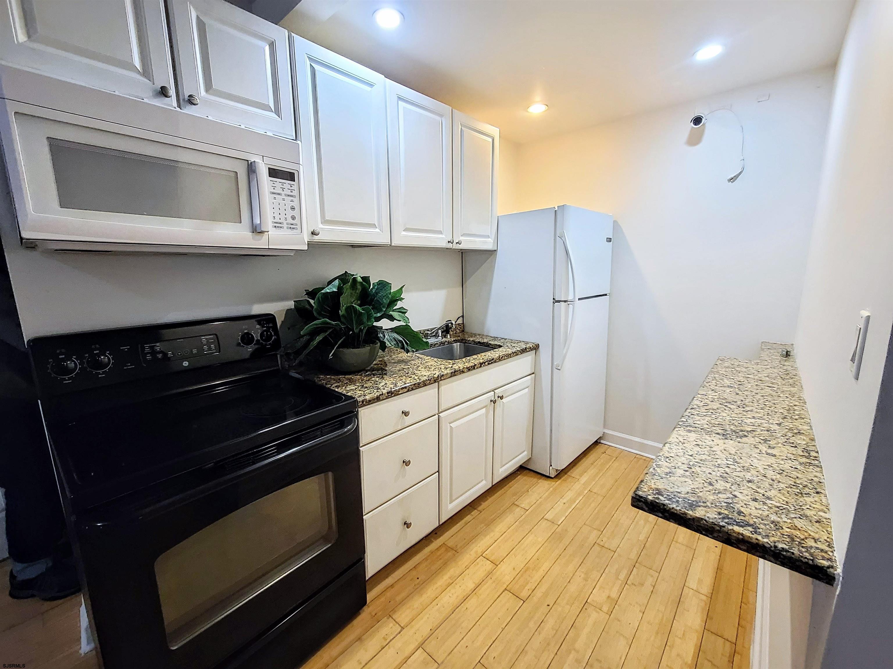 711 Wisteria Road Chelsea Heights, NJ 08401 - Photo 2 of 26 a kitchen with granite countertop white cabinets and stainless steel appliances
