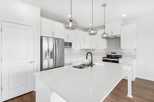 a kitchen with stainless steel appliances a sink a stove a refrigerator and cabinets