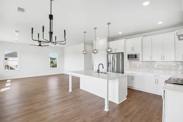 a large kitchen with stainless steel appliances kitchen island a large counter top and wooden floors
