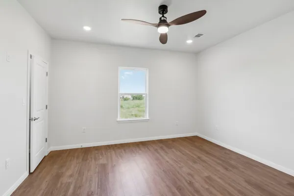 an empty room with wooden floor and windows