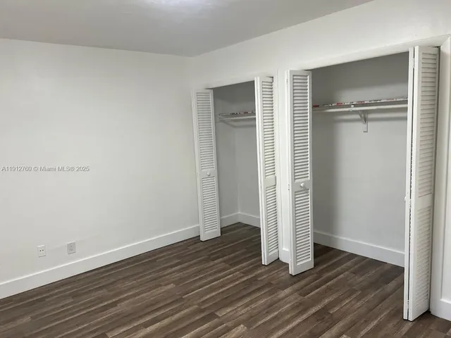 an empty room with wooden floor & closet area