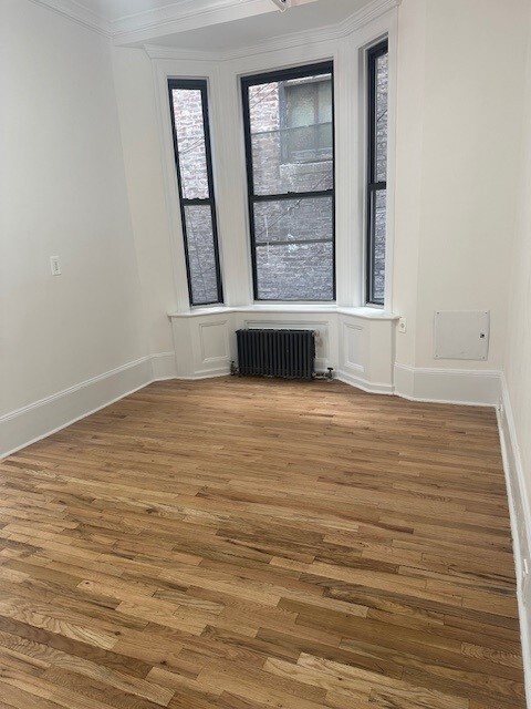 210 5th Avenue, Unit SUITE1102 Manhattan, NY 10010 - Photo 2 of 5 a view of an empty room with wooden floor and a window
