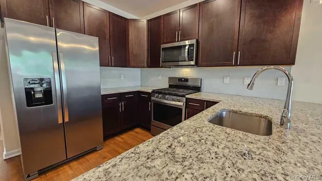 a kitchen with granite countertop a refrigerator and a sink