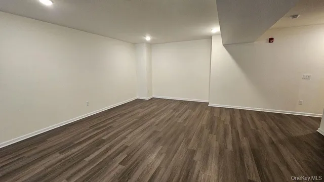 an empty room with wooden floor closet and windows