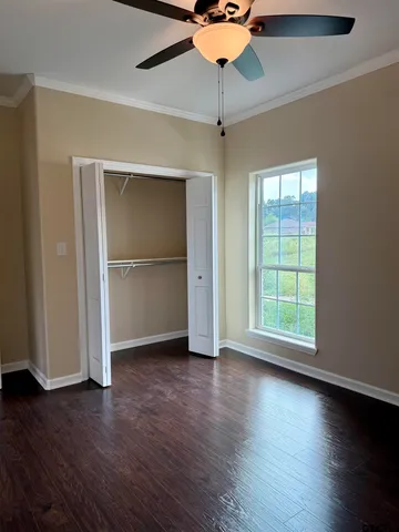 an empty room with wooden floor closet chandelier fan and windows