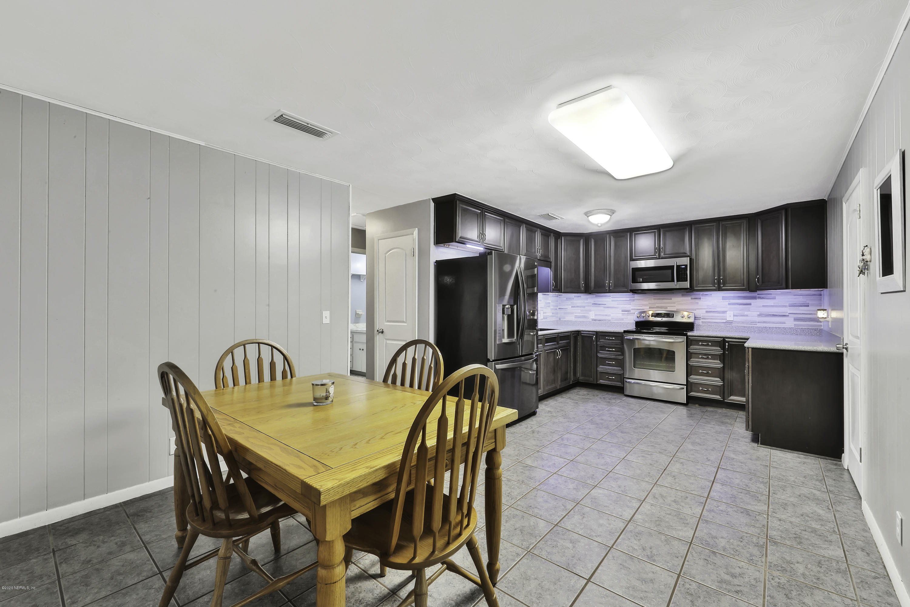 6161 Carlton Road Jacksonville, FL 32244 - Photo 7 of 26 a kitchen with stainless steel appliances kitchen island granite countertop a table chairs microwave and sink