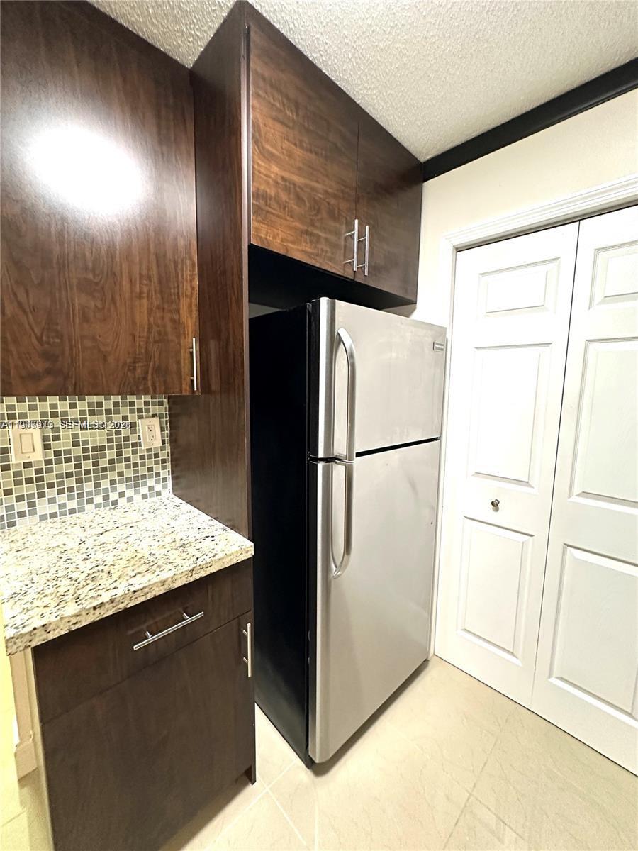919 Northeast 199th Street, Unit 104 Miami, FL 33179 - Photo 16 of 19 a kitchen with stainless steel appliances granite countertop a refrigerator and a sink