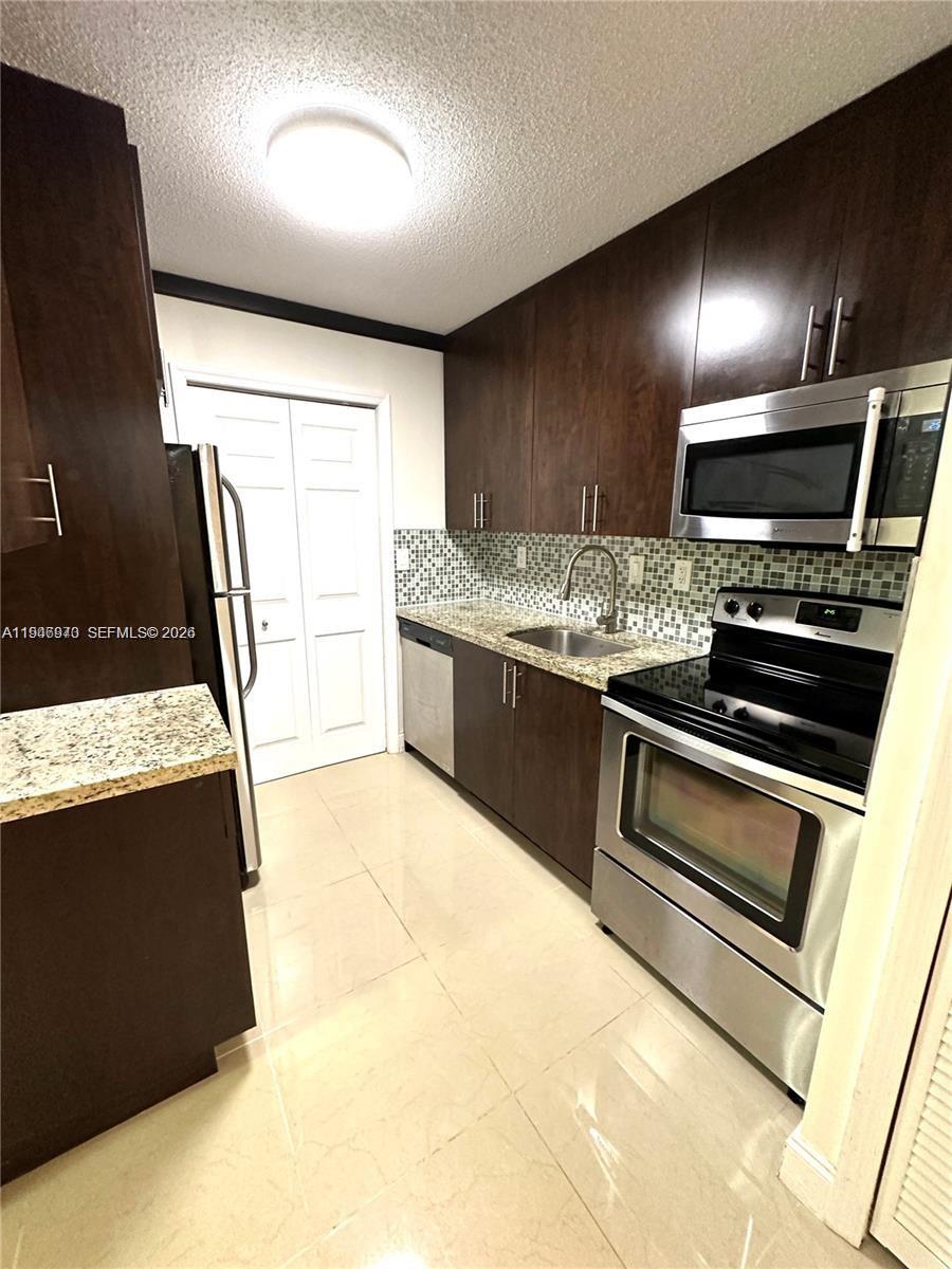 919 Northeast 199th Street, Unit 104 Miami, FL 33179 - Photo 4 of 19 a kitchen with stainless steel appliances a stove microwave and sink