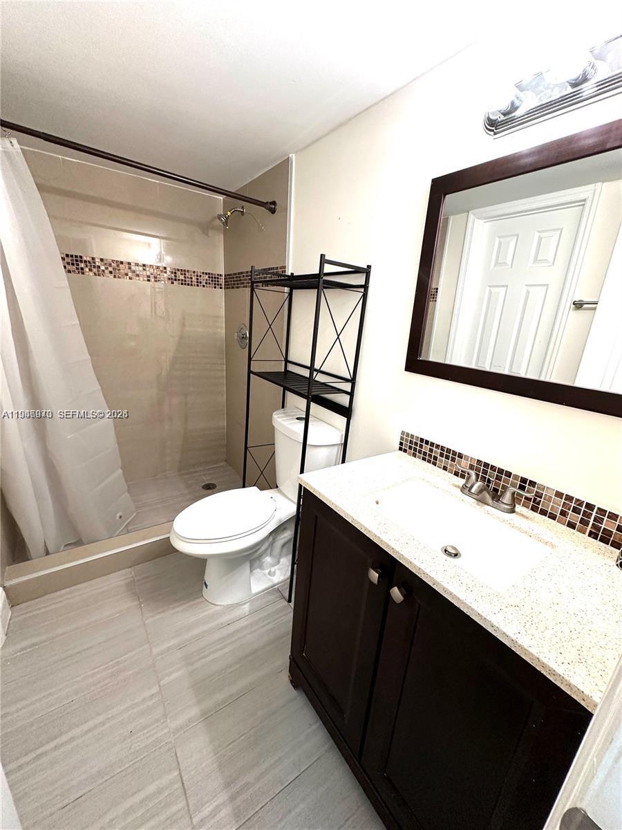 919 Northeast 199th Street, Unit 104 Miami, FL 33179 - Photo 7 of 19 a bathroom with a sink a toilet a mirror and shower