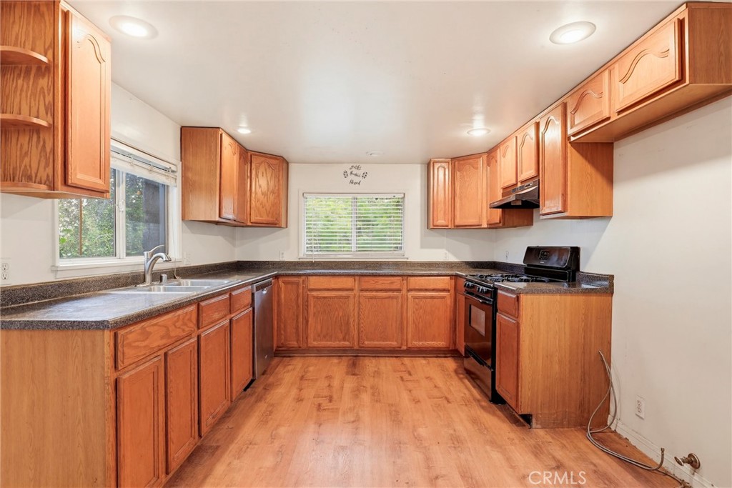 7264 Hillrose Street Tujunga, CA 91042 - Photo 11 of 27 a kitchen with stainless steel appliances granite countertop wooden cabinets a stove a sink and a window
