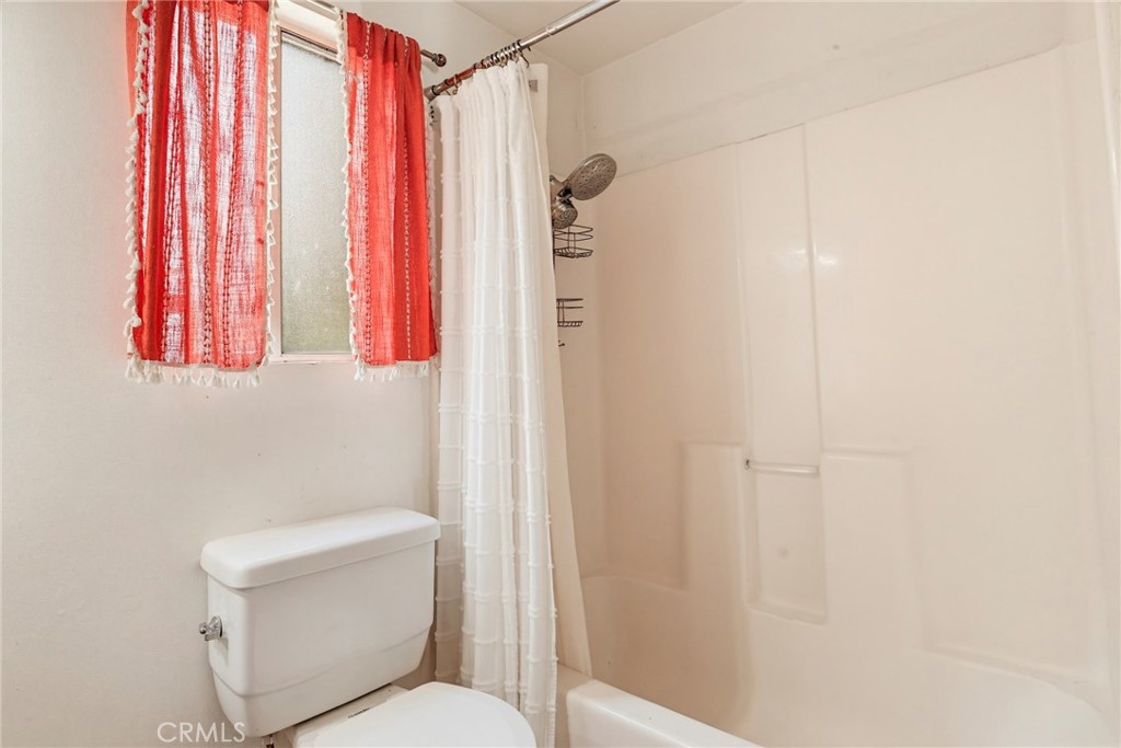 7264 Hillrose Street Tujunga, CA 91042 - Photo 17 of 27 a white toilet sitting next to a shower curtain