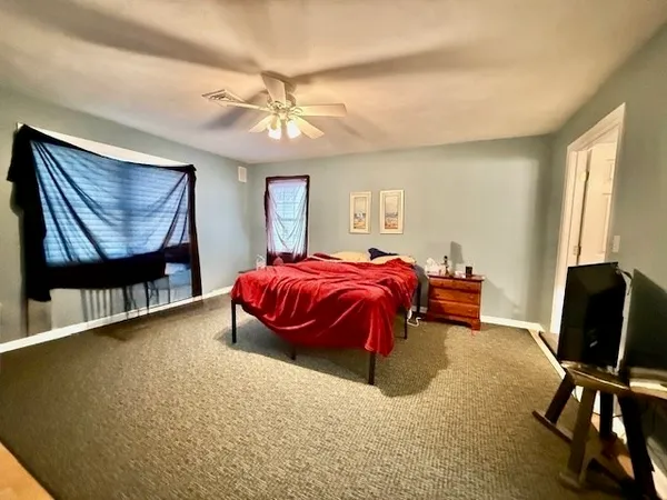 a spacious bedroom with a bed a dresser and a chandelier