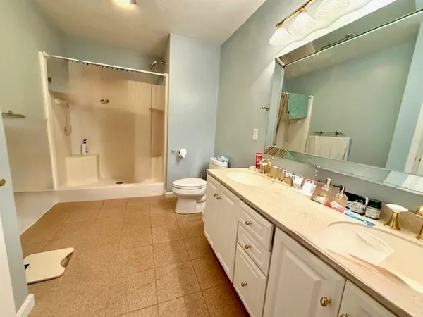 a spacious bathroom with a double vanity sink toilet mirror and shower