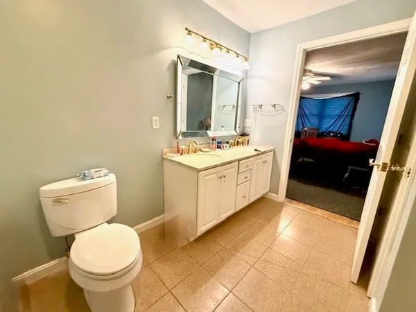 a bathroom with a toilet sink vanity and mirror