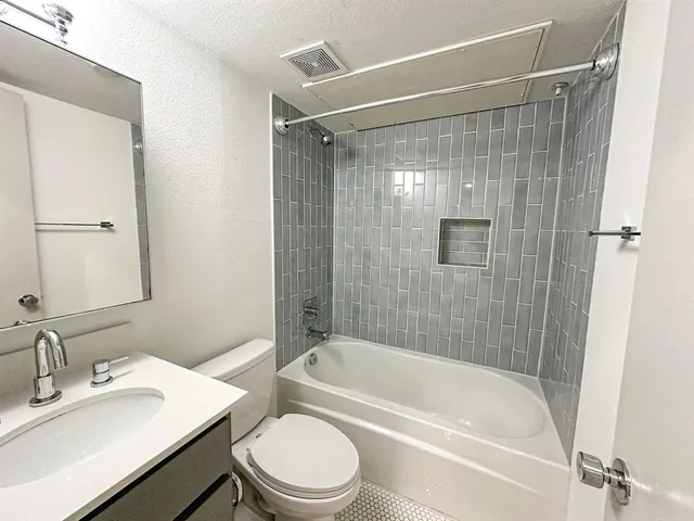 a bathroom with a bathtub shower sink vanity and toilet