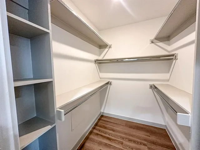 a view of walk in closet with wooden floor