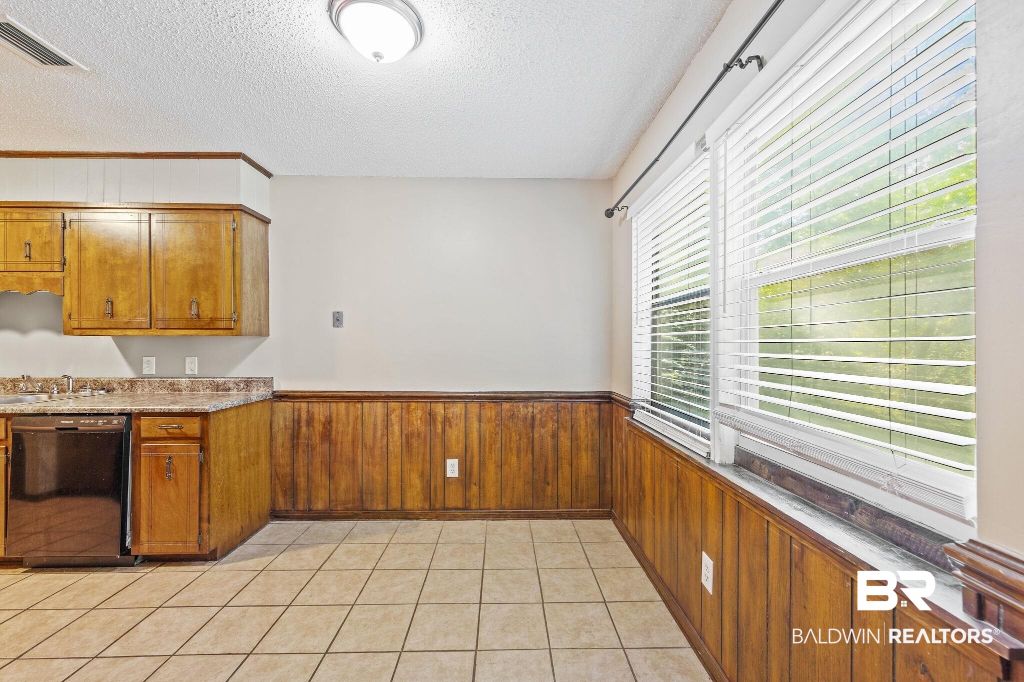 4151 Springdale Road Mobile, AL 36609 - Photo 17 of 21 Kitchen featuring dishwasher, wooden walls, a textured ceiling, and light tile patterned flooring
