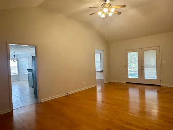 a view of an empty room with window and wooden floor