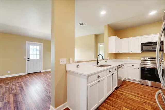 a kitchen with stainless steel appliances granite countertop a sink and cabinets with wooden floor