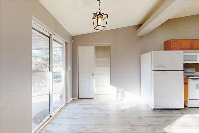 a view of a kitchen with wooden floor and refrigerator