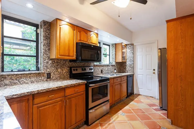 a kitchen with stainless steel appliances granite countertop a stove a sink and a microwave