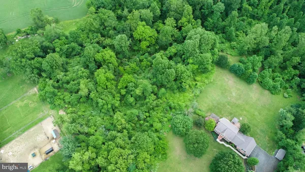 an aerial view of residential house with outdoor space and trees all around
