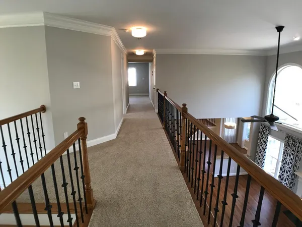 a view of a hallway with wooden floor and stairs