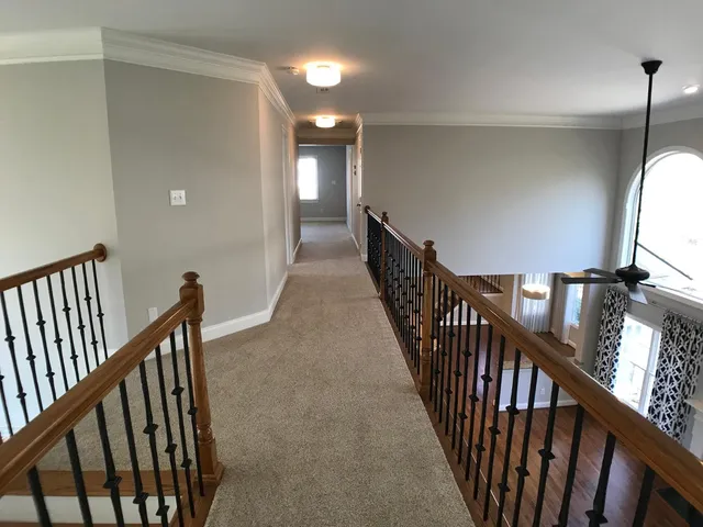 a view of a hallway with wooden floor and stairs