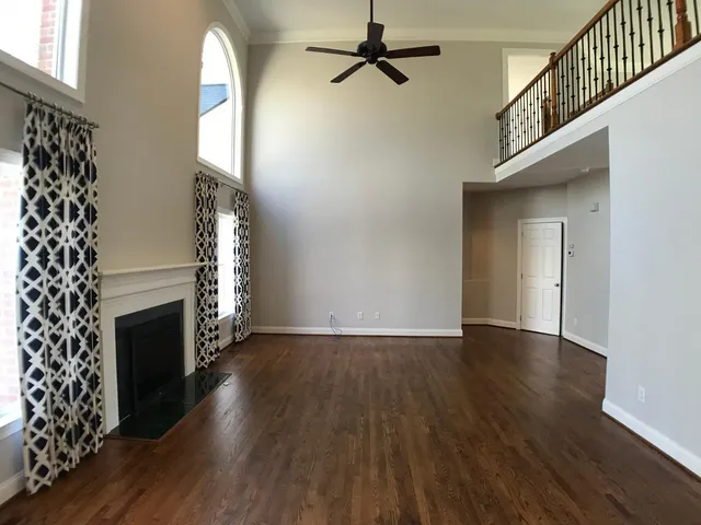 a view of an empty room with wooden floor and a fireplace
