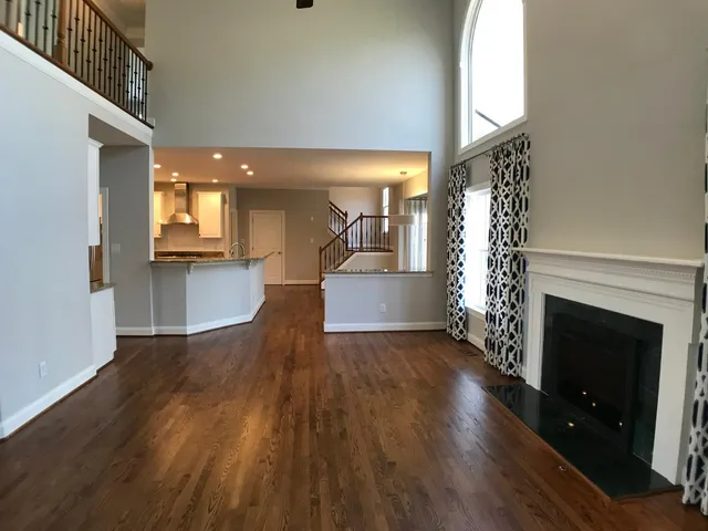 an empty room with wooden floor fireplace and windows
