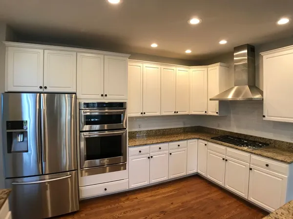 a kitchen with granite countertop white cabinets and stainless steel appliances
