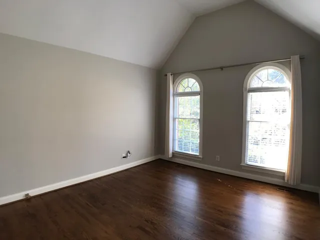 an empty room with wooden floor and windows with curtains view