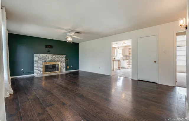 an empty room with wooden floor fireplace and windows