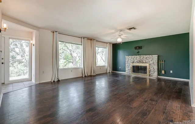 a view of an empty room with a window and wooden floor