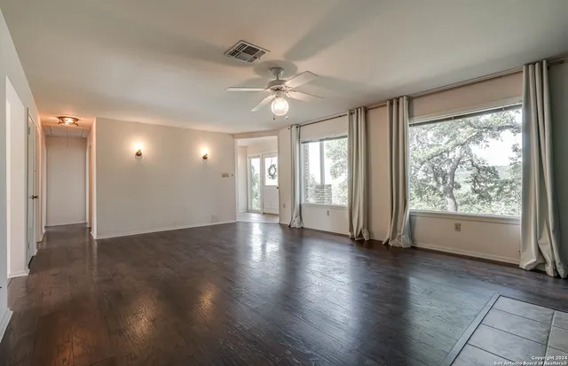 a view of an empty room with wooden floor and a window