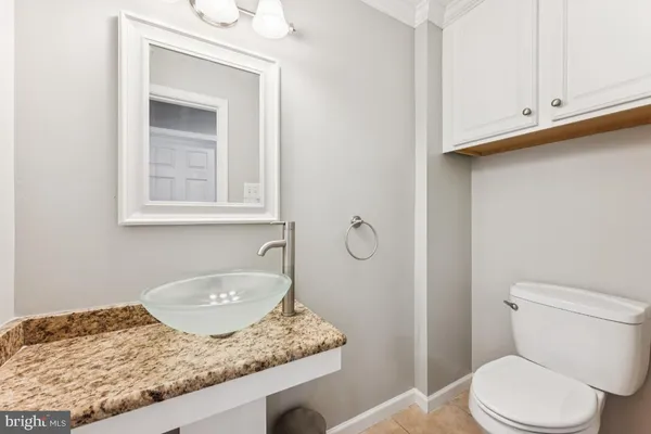 a bathroom with a granite countertop sink toilet and mirror