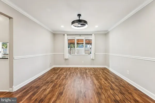 an empty room with wooden floor cabinet and windows