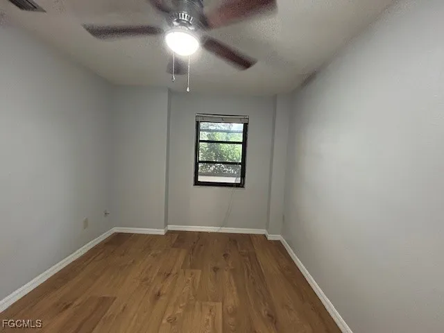 an empty room with wooden floor cabinet and windows