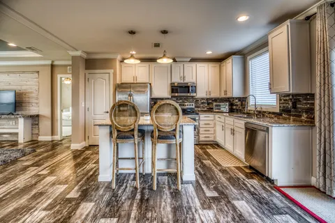 a kitchen with stainless steel appliances granite countertop a refrigerator a stove and a sink with wooden floor
