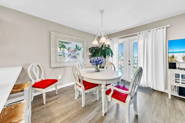 a dining room with furniture a rug a potted plant and wooden floor
