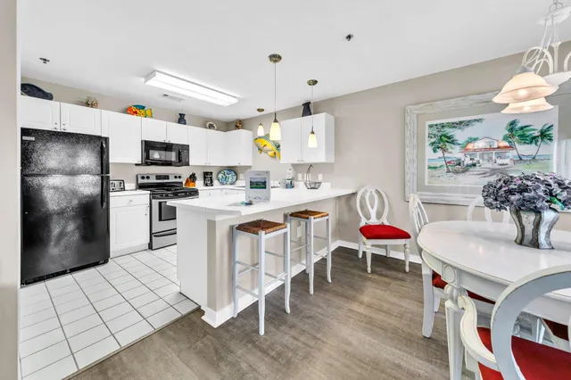 a kitchen with stainless steel appliances a stove a sink a microwave a refrigerator and chairs